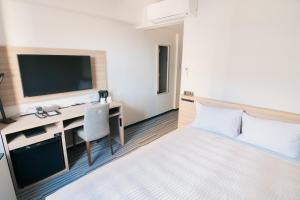 a hotel room with a bed and a desk with a television at クインテッサホテル千葉船橋 in Funabashi
