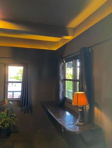 a room with a table with a lamp and two windows at Mojo Hostel in Puerto Princesa City