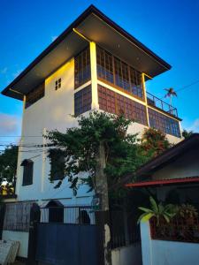 uma casa branca com uma árvore em frente em Mojo Hostel em Puerto Princesa