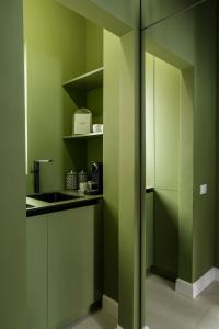 a green kitchen with a sink and a refrigerator at ROUGE Studio in Bucharest in Bucharest