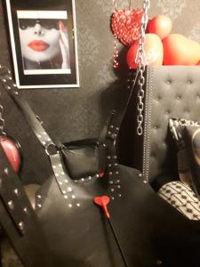Una silla negra con un par de tijeras rojas. en LOVE ROOM Le rouge et noir, en Barr