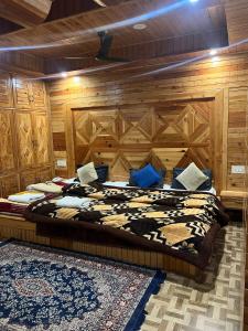 a bedroom with a large bed with a wooden wall at The Lalits Kitchen in Kasol