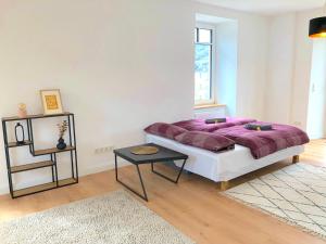 ein Schlafzimmer mit einem lila Bett und einem Tisch in der Unterkunft Modernes Apartement mit Balkon in Toplage! in Traben-Trarbach