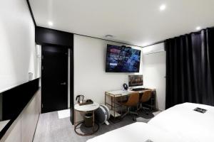 um quarto com uma cama, uma secretária e uma televisão em Hotel In Modern em Cheongju