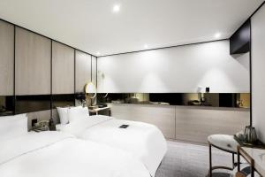 a bedroom with two white beds and a kitchen at Hotel In Modern in Cheongju