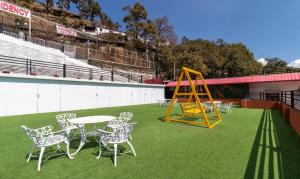 a playground with a table and chairs on a field at Treebo Trend Stotrak S N Residency - Mussoorie in Mussoorie