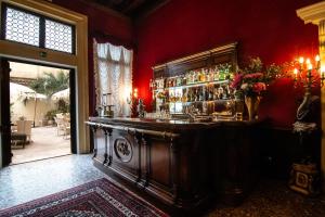 - un bar dans une pièce dotée d'un mur rouge dans l'établissement Palazzo Paruta & Wellness Suites, à Venise