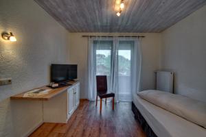 a room with a bed and a desk with a television at Trail Hotel Oberstaufen in Oberstaufen