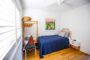 een slaapkamer met een blauw bed en een stoel bij White Lilly Retreat in Gerringong