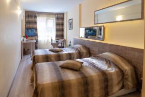 a hotel room with two beds and a mirror at Supreme Victoria in Varna City