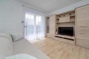 a living room with a white couch and a television at Beautiful Apartment with a Spacious Balcony in Wrocław by Renters in Wrocław