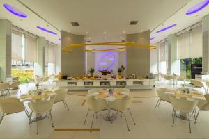 Un comedor con mesas y sillas y una cocina. en Hotel Kohinoor Elite near BKC, en Bombay