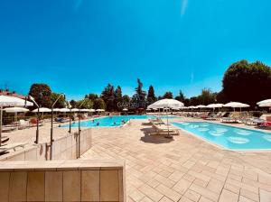 ein großer Pool mit Stühlen und Sonnenschirmen in der Unterkunft Flora Apartment - 100 metri dal Lago di Garda - Piscina in Sirmione