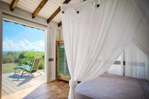 ein Schlafzimmer mit einem Himmelbett und einem Stuhl auf einer Terrasse in der Unterkunft Pointe des Châteaux in Saint-François