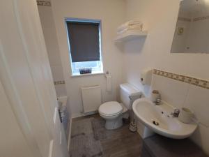La salle de bains blanche est pourvue de toilettes et d'un lavabo. dans l'établissement J's House, à Nottingham