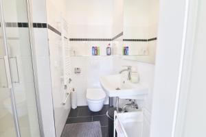 a white bathroom with a toilet and a sink at Moderne helle Ferienwohnung Allgäu am See Munich Castle in Lechbruck