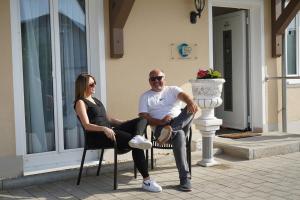 mężczyzna i kobieta siedzący na krześle przed budynkiem w obiekcie Eco Motel w mieście Wallersdorf