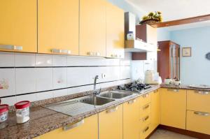 a kitchen with yellow cabinets and a sink at 3 bedrooms apartement with sea view enclosed garden and wifi at Posada 2 km away from the beach in Posada