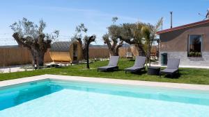 una piscina con 2 sillas y un patio con árboles en Giuliv Home Deluxe, en Piazza Armerina