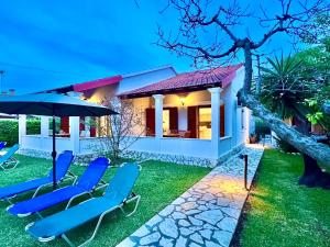 a house with blue lawn chairs and an umbrella at Beachfront Suites GardenMare by DadoVillas in Litherés