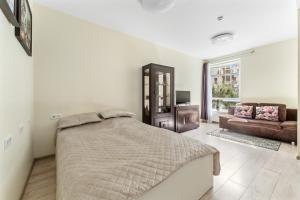 a white bedroom with a bed and a couch at Ozo park apartments in Vilnius