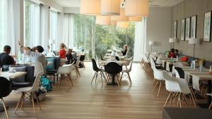 a restaurant with tables and chairs and people sitting at tables at Hotel FairPlayce in Poznań