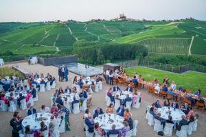 een groep mensen die aan tafels voor een evenement zitten bij Foresteria Castello di Perno in Monforte dʼAlba