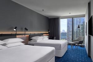 a hotel room with two beds and a large window at Vibe Hotel Melbourne Docklands in Melbourne