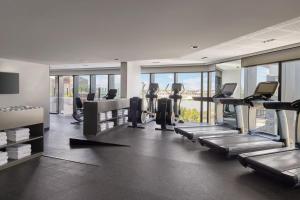 a gym with treadmills and ellipticals and windows at Vibe Hotel Melbourne Docklands in Melbourne