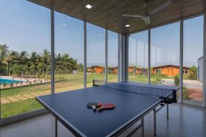 a ping pong table in a room with large windows at Aveeno Resort with Swimming Pool Near Calangute & Baga in Goa