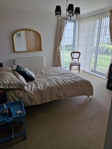 a bedroom with a bed with a mirror and a chair at Beachside Ground Floor Flat in Birchington