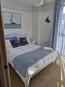ein Schlafzimmer mit einem Bett mit einer blauen Decke und einem Fenster in der Unterkunft Beachside Ground Floor Flat in Birchington