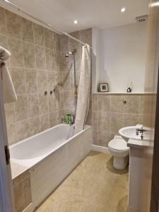 ein Badezimmer mit einer Badewanne, einem WC und einem Waschbecken in der Unterkunft Beachside Ground Floor Flat in Birchington