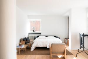 a white bedroom with a bed and a tv at Queens Courtyard by Daniel&Jacob's in Copenhagen