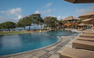 a pool at a resort with a view of the ocean at MERUSAKA Nusa Dua in Nusa Dua