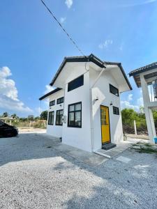 un edificio blanco con una puerta amarilla en un estacionamiento en Memerang Tiny House & Pool 4 pax Merang, en Setiu