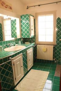 La salle de bains carrelée de couleur verte est pourvue d'un lavabo et d'un miroir. dans l'établissement Vista Panoramica a 5 minuti dal Lago Liscia, à Sant Antonio Di Gallura
