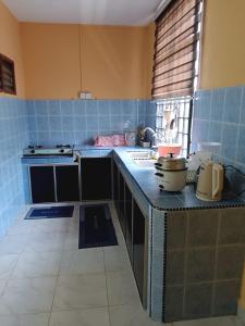 a blue tiled kitchen with a counter top with a stove at CHE SUE HOMESTAY 02 in Pasir Mas