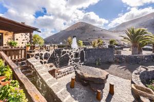 a stone patio with a table and a mountain at Casa Rural Vega de Timanfaya in Uga