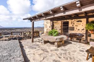 a stone patio with a bench and a table at Casa Rural Vega de Timanfaya in Uga