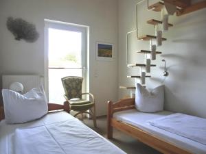 Cette chambre dispose de deux lits, d'une chaise et d'une fenêtre. dans l'établissement Ferienwohnung E8, à Graal-Müritz