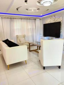 a living room with white furniture and a flat screen tv at GEORGE B BOUTIQUE LODGE in Tzaneen