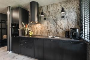 a kitchen with black cabinets and a marble wall at Apartament 717 - z sauną in Szczawnica