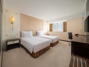 a hotel room with two beds and a flat screen tv at Dorsett Chengdu in Chengdu