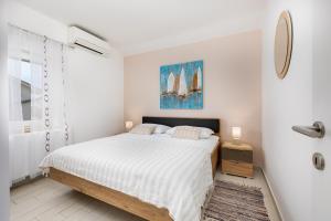 a white bedroom with a bed and a window at Apartment Neda in Krk