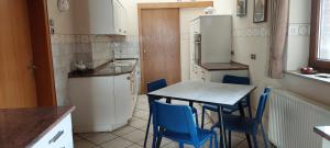 een kleine keuken met een tafel en blauwe stoelen bij Fewo Haus Cäcilia in Elsdorf