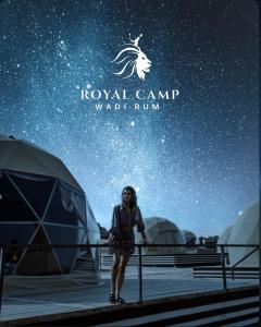 a woman standing in front of tents under a starry sky at ROYAl WADI RUM CAMP in Wadi Rum