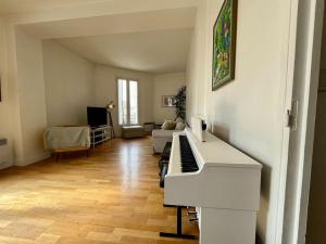 - un salon avec un piano blanc et un canapé dans l'établissement Bienvenue, à Montrouge