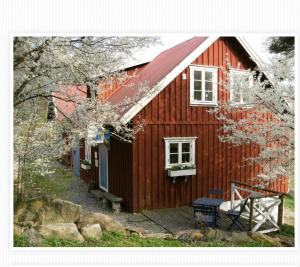 uma casa vermelha com um banco à frente em Finas Torpgård B&K em Gällinge