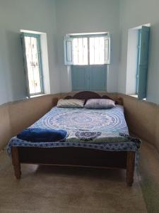 a bed in a room with two windows at Shanthi House in Mysore